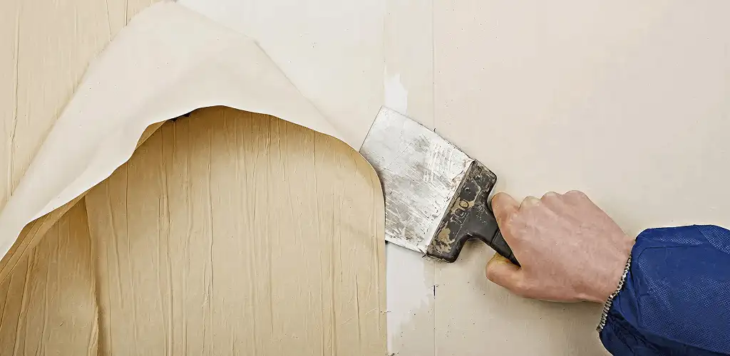 Handyman removing wallpaper with a scraper for wall preparation in Chicago, IL