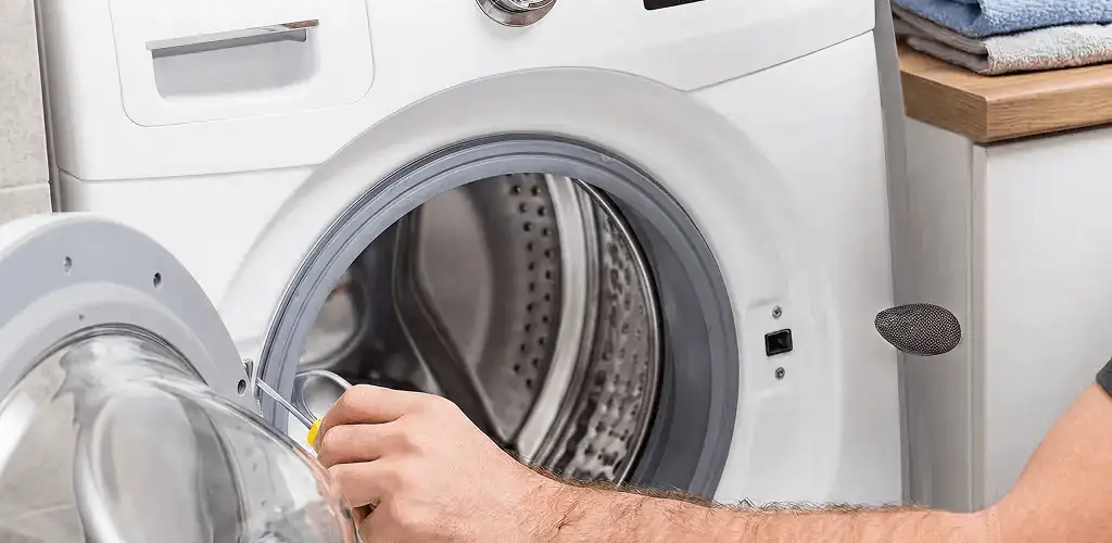 Handyman repairing a front-load washing machine and inspecting the drum in Chicago, IL