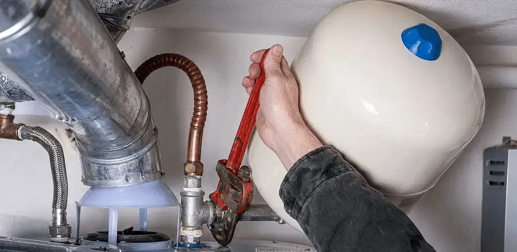 Water heater repair technician tightening plumbing connections near a tank unit in Chicago, IL
