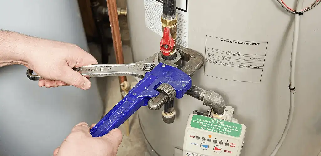 Water heater repair technician tightening the shutoff valve and supply line in Chicago, IL